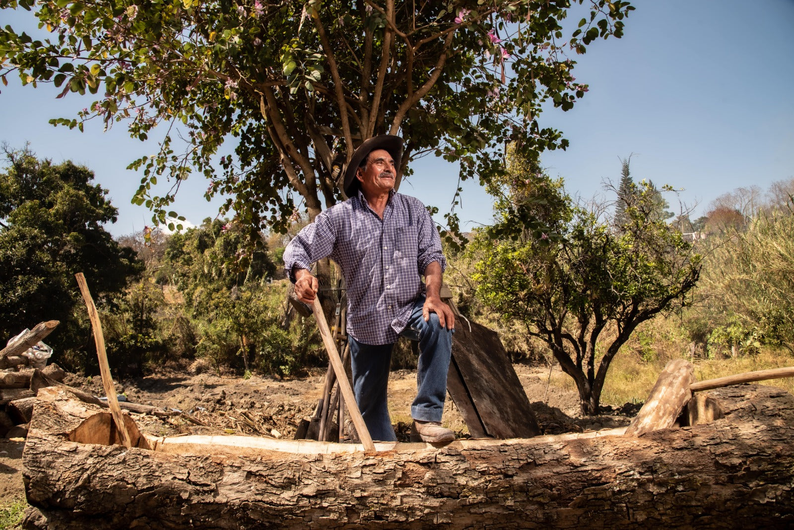 Maestro mezcalero sosteniendo un mazo de madera con el que golpea el maguey para molerlo